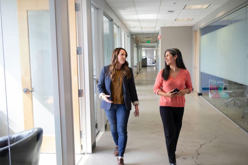 A commercial cleaning estimator walking through an office space with a clipboard and floor plan, measuring square footage for a bid